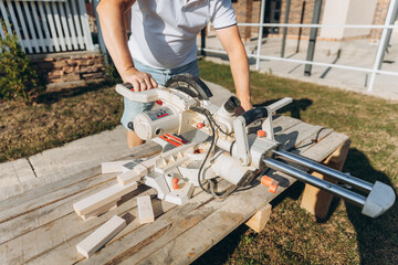 male carpenter cuts a wooden board with an electric saw at home. builder.