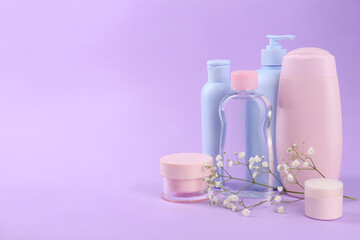 Obraz na płótnie Canvas Different skin care products for baby and gypsophila on violet background. Space for text