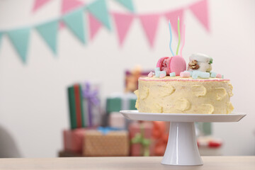 Delicious cake decorated with macarons and marshmallows on wooden table in festive room, space for...