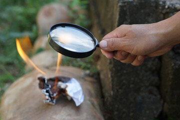 Close up hand hold magnifying glass to make fire for burning paper. Concept, Science experiment...