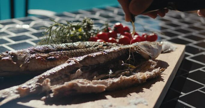 Cook hand olive oil season mullet fish grill dinner table in close up