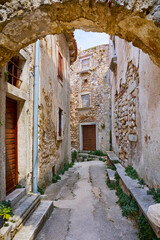 Croatia Istria. Ancient abandoned medieval town Plomin. Arch at the old stone street with ruined walls houses and stairs