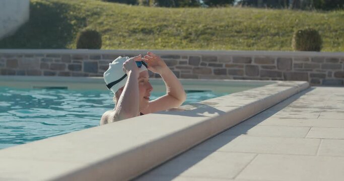Swimmer woman on edge put on goggles backstroke swim in swimming pool