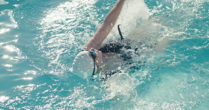 Swimmer woman push edge backstroke swims in swimming pool in close up