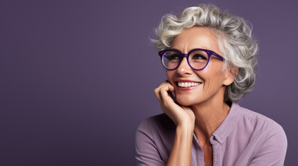 A middle-aged woman with gray hair smiles and looks away against a purple background