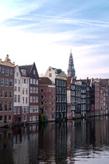 Fototapeta na wymiar Old buildings of Amsterdam near river. Reflections in the morning on a canal of Amsterdam, Holland 