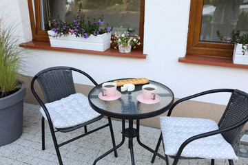 Cups of coffee, bread and cheese on glass table. Relaxing place at outdoor terrace