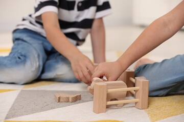 Little children playing with set of wooden animals indoors, closeup