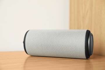One portable bluetooth speaker on wooden table. Audio equipment