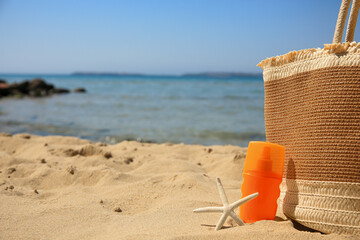Sunscreen, starfish and bag on beach, space for text. Sun protection care