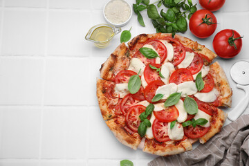 Delicious Caprese pizza with tomatoes, mozzarella and basil served on white tiled table, flat lay. Space for text