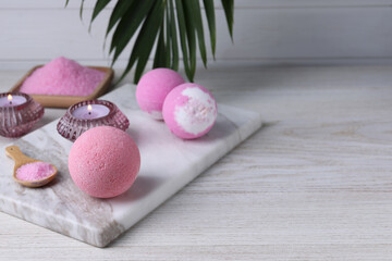 Beautiful composition with aromatic bath bombs on white wooden table, space for text