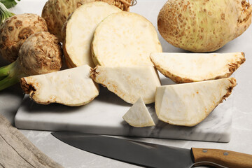 Whole and cut celery roots on light grey table