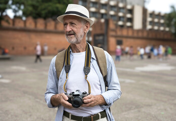 Senior Caucasian tourist holding camera during visitting Tha Pae Gate, Chiangmai Thailand during...