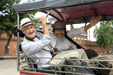 Senior tourist couples sitting in tuk tuk during summer vacation in Thailand