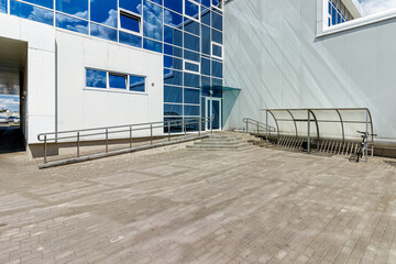 Entrance to a modern glass building, with bicycle parking and a ramp for the disabled