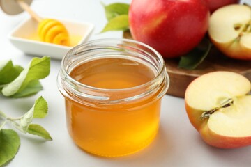 Sweet honey and fresh apples on white table, closeup