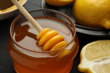 Sweet honey and fresh lemons on black table, closeup