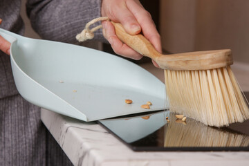 Close up image of woman's hands cleaning apartment with small broom and dustpan