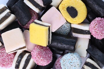 Many tasty liquorice candies on white background, top view