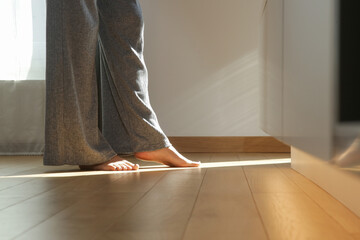 Barefoot woman on the wooden floor. Concept of the underfloor heating in the apartment.	