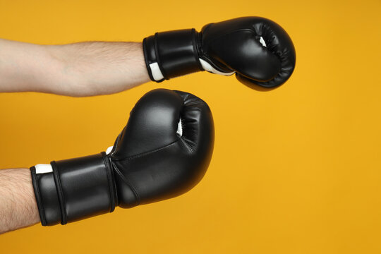 Black boxing gloves on a yellow background