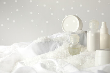 Cosmetic jars and snow on white background, space for text
