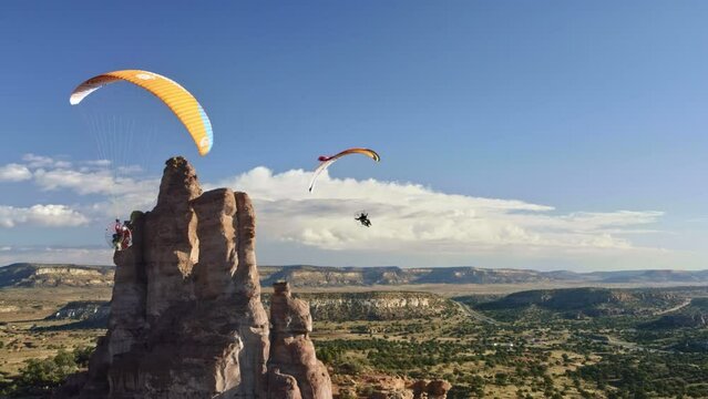 Paramotors Flying Around Desert Rock Pillar - drone, slow motion shot