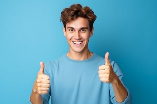 Young Man Showing Thumbs Up On Blue Background