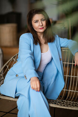 Elegant young woman posing sit on a sofa, looking at camera.