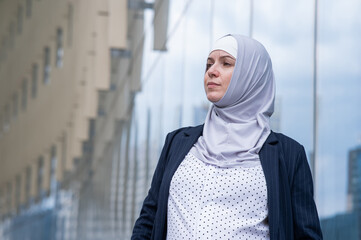 Portrait of pensive business woman in hijab and suit outdoors. 