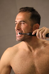 Przystojny, dojrzały mężczyzna myje zęby.
A man brushes his teeth with an electric toothbrush.