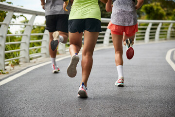 close-up shot of legs and feet of group of young asian adults people running jogging outdoors - obrazy, fototapety, plakaty