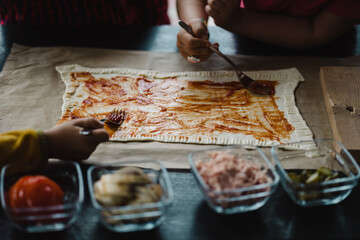 The process of making homemade pizza, rolled out dough on which various ingredients are placed on...