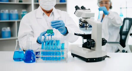 Fototapeta premium Scientists conducting research investigations in a medical laboratory, a researcher in the foreground is using a microscope in laboratory for medicine. .