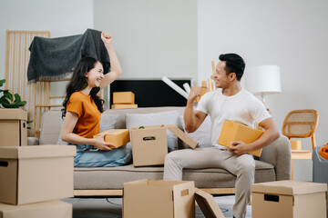 Asian young attractive couple man and woman use tablet and smartphone online shopping furniture decorate house with carton package move in new house. Young married asian moving home. .