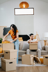 Asian young attractive couple man and woman use tablet and smartphone online shopping furniture decorate house with carton package move in new house. Young married asian moving home. .