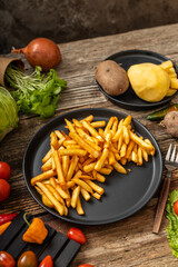 French fries served on black plate and wooden table
