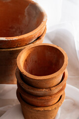 Untreated clay pots. Orange color. Autumn mood. Against the background of a delicate white curtain. Daylight. Natural color.