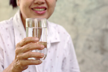 woman holding a glass of water Drinking enough water per day promotes good health.