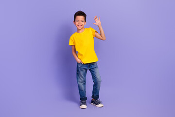 Full length photo of nice young pupil boy wave hand hello shopping dressed yellow garment isolated on violet color background © deagreez
