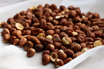 Fresh, young, unroasted hazelnuts or hazelnut kernels. Against the background of a delicate white curtain. Daylight. Natural color.