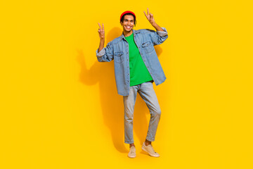 Full body photo of attractive young man showing double v-sign dressed stylish jeans clothes isolated on yellow color background
