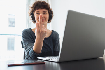 teenage girl shows middle finger while sitting in front computer