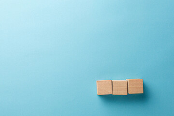 wooden cubes three pieces in a row on a blue background