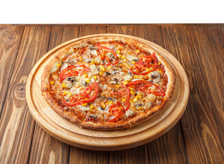 delicious pizza with chicken, mushrooms, cheese, tomatoes and corn on a wooden background
