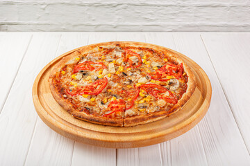 delicious pizza with chicken, mushrooms, cheese, tomatoes and corn on a wooden background