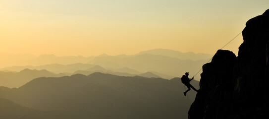 Man Climbing a Great Rock in a Sunset Landscape