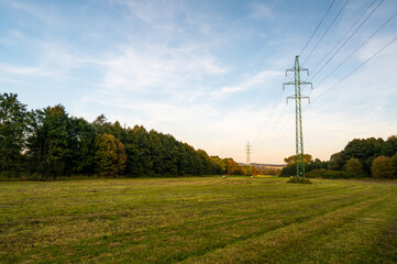 High voltage power line on agriculture land at meadow.