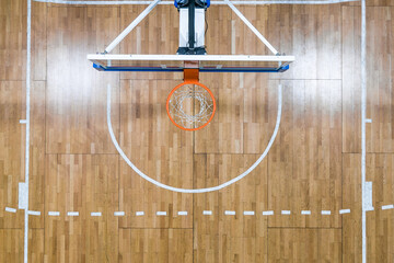 Top view of a basketball hoop against the backdrop of a parquet basketball court